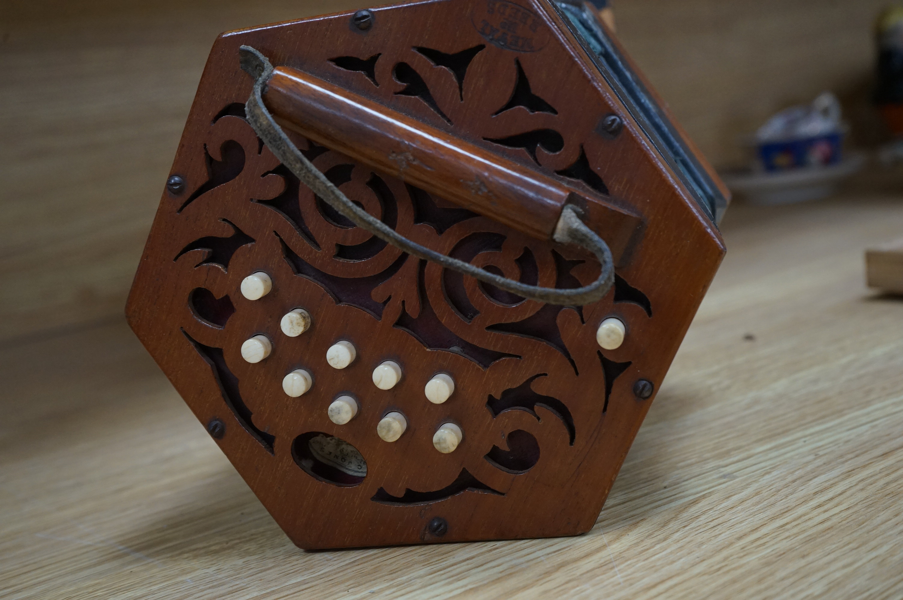 A cased accordion with paper label for C. Jones, bone buttons, 17cm wide. Condition - box worn, accordion strap torn and leather rubbed to edges of accordion